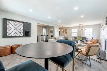 an open living room with a round table and chairs and a kitchen with a table
